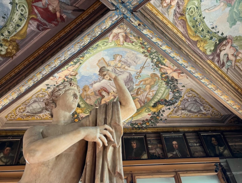 A statue and view of the frescoed ceiling in the Uffizi.